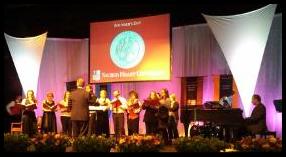 University recognition event on stage with LED lighting and triangle banners - Sacred Heart Univ   SHU
